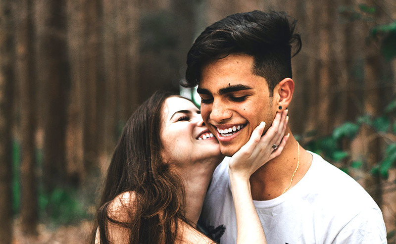 男性の頬に笑いながらキスをしようとする女性