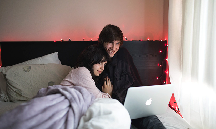 ベッドでパソコンを見ているカップル
