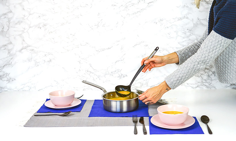 鍋からスープを注ぐ女性
