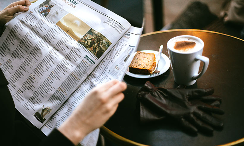 カフェで新聞を読む男性
