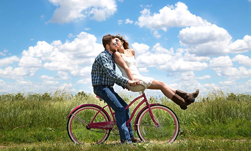 自転車のハンドルに乗っている女性にキスをする男性
