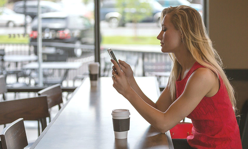 カフェでスマートフォンを見ている女性