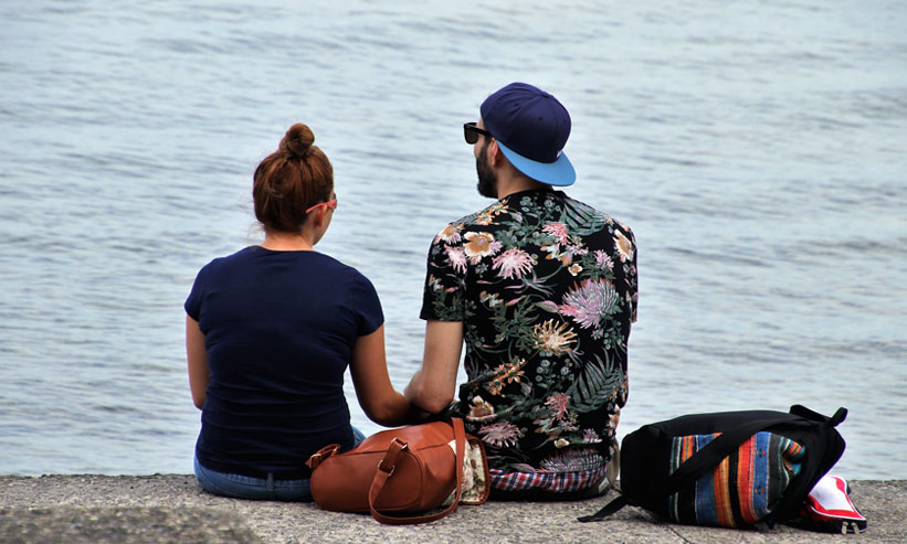 座って海を眺めるカップル