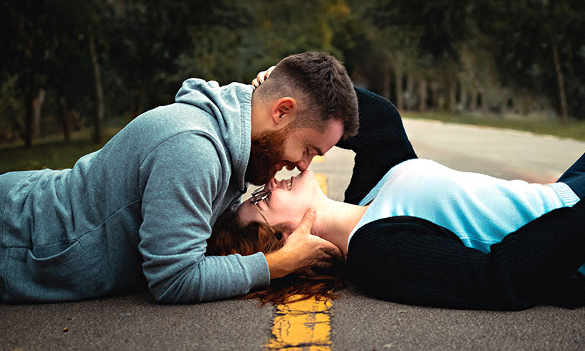 道路に寝そべりキスをするカップル