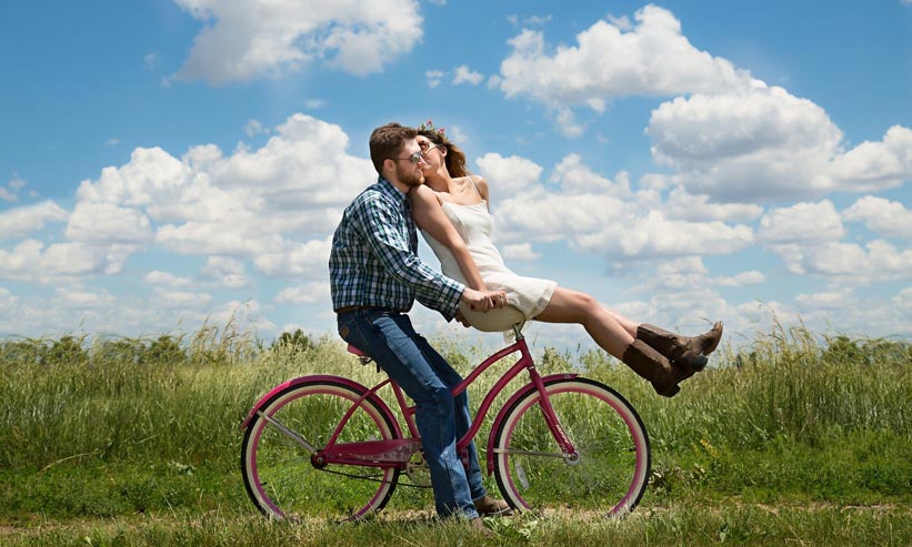 自転車に乗っている男性とハンドルに座り男性にキスをしている女性