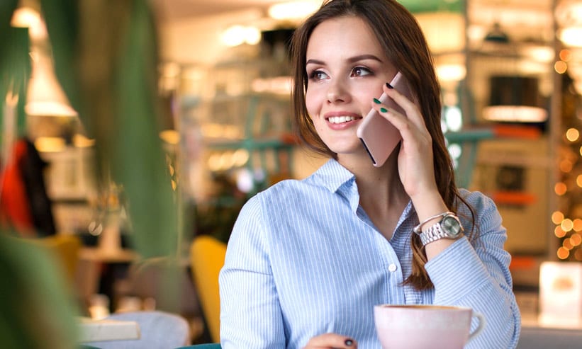 カフェでコーヒーを飲みながら電話をしている女性