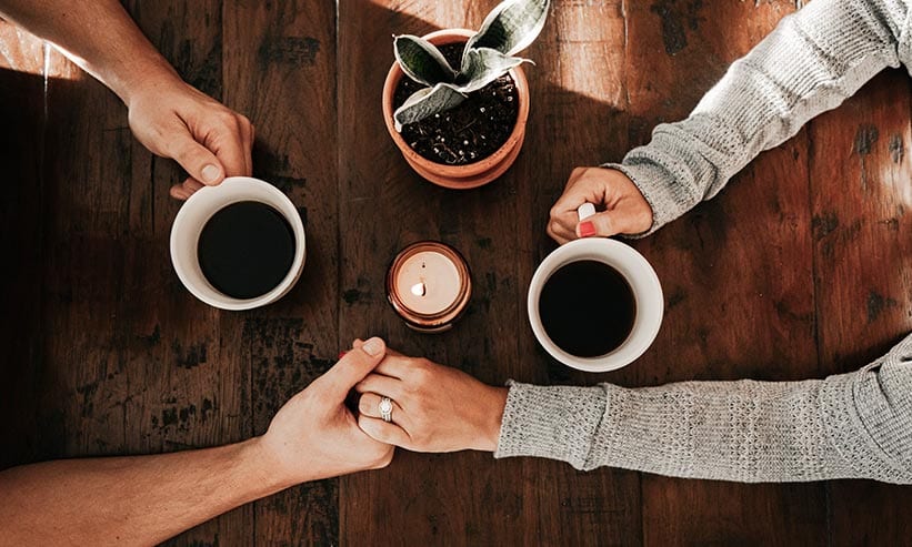 コーヒーを持ちながら手を繋いでいるカップル