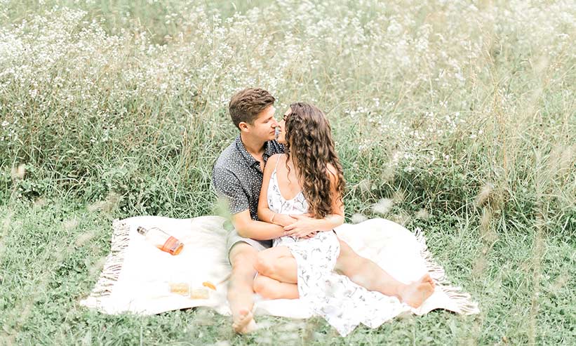 草原に座りキスをするカップル