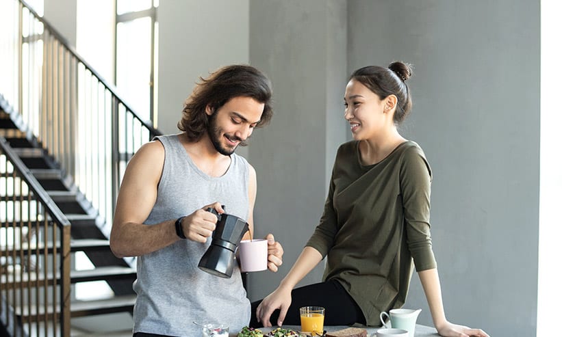 リビングでコーヒーを飲みながら話をしているカップル