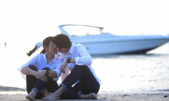 湖の前に座りキスをするカップル